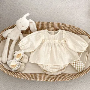 Détail de la blouse brodée et du short bouffant pour bébé dans un panier tressé