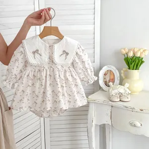 Détail d'un body floral pour bébé avec col Claudine en dentelle et broderie