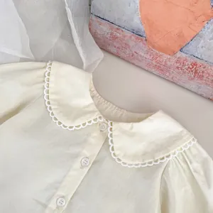 Detail of cream baby shirt featuring a Peter Pan collar with delicate white lace trim