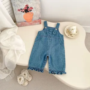 Détail d'une salopette en jean pour bébé avec ourlet à volants et boutons-pression