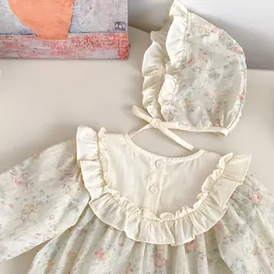 Dettaglio del body neonata a fiori con colletto a ruche e cappellino in cotone crema