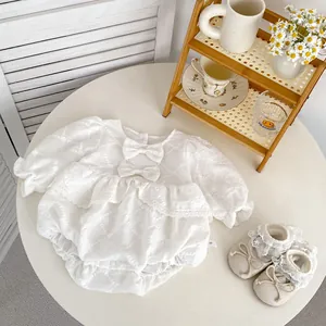 Flat lay of baby girl white lace romper with bow details and matching infant shoes