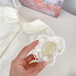 Close-up of baby shirt featuring Peter Pan collar with lace trim and elastic cuffs