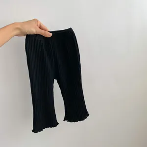 Close-up of black ribbed baby leggings with ruffled lettuce edges and elastic waist details