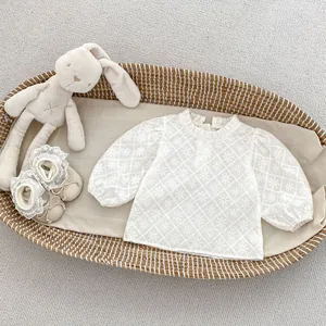 Détail d'un haut à manches longues en dentelle brodée pour bébé et chaussures assorties