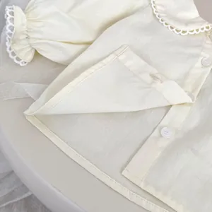 Detail of baby girl cream blouse featuring Peter Pan collar and delicate lace embroidery