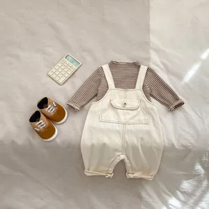 Ensemble bébé avec t-shirt rayé, salopette en coton beige et petites chaussures souples
