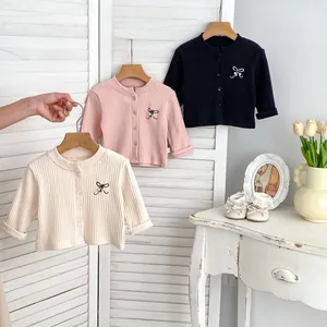Detail of baby knit cardigans with bow embroidery and pearl accents on ribbed cotton fabric