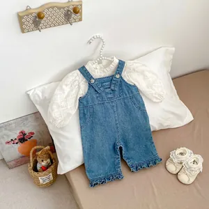 Détail de la salopette en jean pour fille avec haut en dentelle brodée et boutons perles