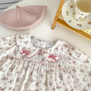 Close-up of floral baby romper with Peter Pan collar and pink velvet bows detail