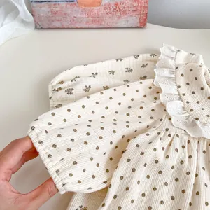 Detailed close-up of baby romper featuring delicate lace collar and floral polka dot fabric