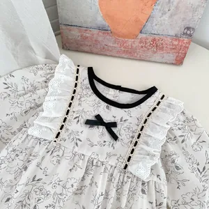 Floral baby girl romper with lace ruffles and black bow in cream cotton fabric