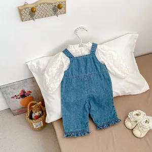Détail de la broderie florale sur le haut blanc et la salopette en jean pour bébé