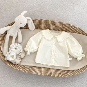 Detail of baby white Peter Pan collar shirt and lace shoes in a woven basket
