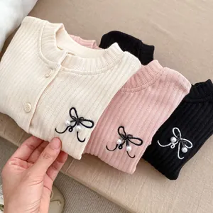 Detail of rib-knit cardigans featuring delicate bow embroidery and pearl accents