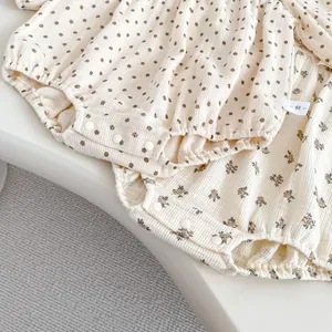Detail of snap button closure and cotton fabric on floral and polka dot baby bodysuits