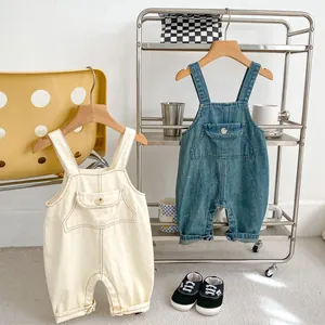 Détail de salopettes en jean pour bébé en crème et bleu avec poches avant et attaches