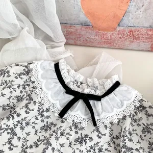 Détail du chemisier floral bébé avec col en dentelle et nœud en velours