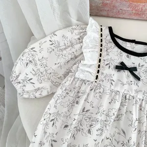 Detail of floral baby bodysuit with lace neckline, black piping and delicate bow