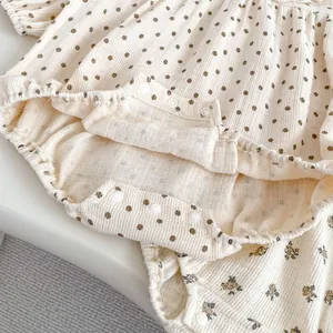 Macro view of cotton baby bodysuit with brown polka dots and bottom snap fasteners
