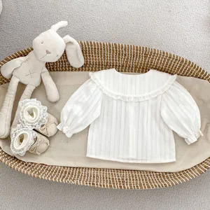 Détail d'un t-shirt bébé blanc à manches longues avec col en dentelle et chaussures assorties