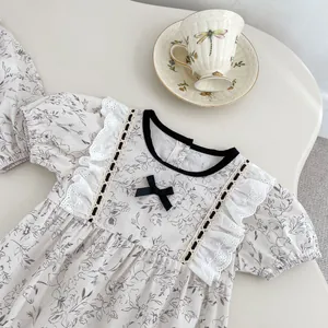 Detail of floral baby bodysuit featuring lace trim and a delicate black ribbon bow
