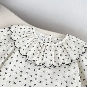 Détail du chemisier bébé en coton avec imprimé nœuds noirs et col à volant brodé