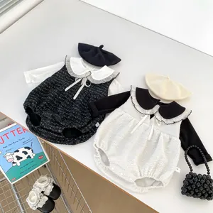Flachliegende Detailansicht von Baby-Stramplern aus Tweed mit Spitzenkragen und Barett
