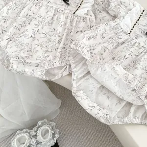 Detail of floral baby bodysuit with lace trim, satin bow, and matching lace socks