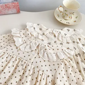 Detail of baby floral bodysuit with lace collar and vintage polka dot print pattern
