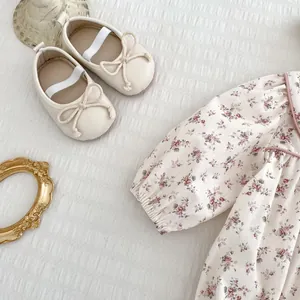 Detailed flat lay of floral baby romper with matching cream bow shoes and vintage frame