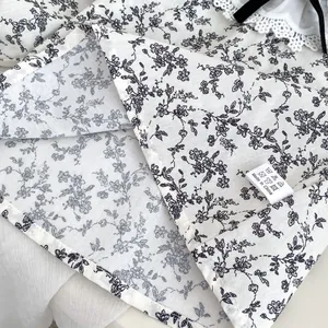 Détail de chemise bébé à fleurs avec col en dentelle, nœud en velours et étiquette