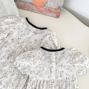 Detailed view of floral baby rompers featuring black round neck and back button closure