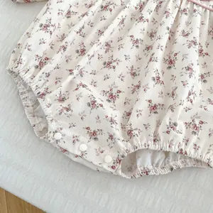 Detail of baby floral romper showing snap button closure and elastic leg openings