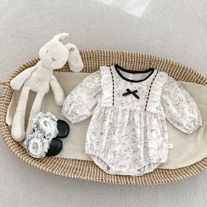 Detail of floral baby bodysuit with lace shoes and bunny toy in a woven basket