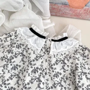 Détail du haut à fleurs pour bébé avec volants en dentelle et noeud en velours noir