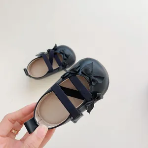 Dettaglio di scarpe Mary Jane nere per neonata con fiocchi e cinturini elastici