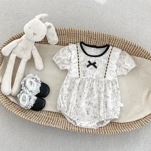 Close-up of floral baby romper with delicate lace bow and matching black soft shoes