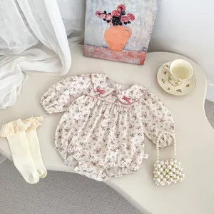 Detailed close-up of floral baby romper with lace socks and a small pearl handbag decor