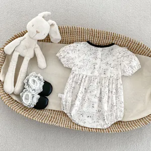 Detail of floral baby bodysuit with puffed sleeves and lace socks in a woven cradle
