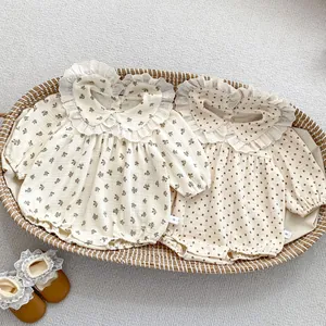 Detail of floral and polka dot baby rompers with lace collars in a woven basket