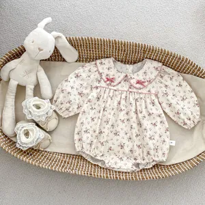 Close-up of floral baby bodysuit with Peter Pan collar and pink bow accents