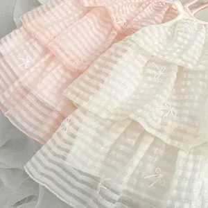 Detail von rosa und beigem Stufenkleid mit Karostruktur und Schleifenstickerei