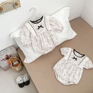 Detail of floral baby rompers featuring cotton fabric, lace ruffles and bow accents