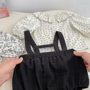 Détail de chemise à fleurs à col volanté et pantalon à bretelles en gaufre