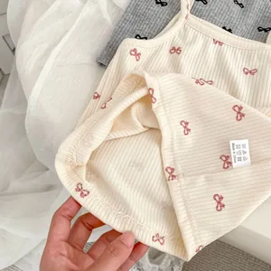 Close-up of girls' knit camisoles with bow prints and detailed laundry care labels