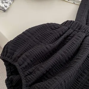 Détail du tissu seersucker noir avec texture gaufrée et design plissé à volants