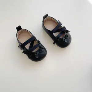 Dettaglio di scarpe Mary Jane nere per neonata con doppi fiocchi e cinturini elastici