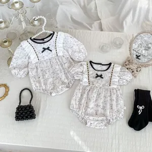 Flat lay of floral baby rompers with elegant lace details and vintage accessories