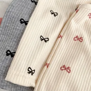Detailed view of ribbed knit fabric featuring cute bow patterns in gray and beige tones